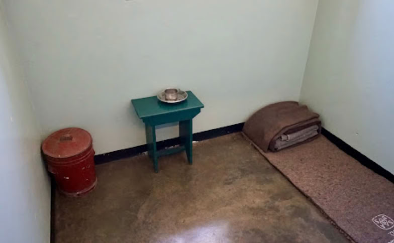 Mandela’s cell as depicted in the early years of incarceration on the island. Later on in his sentence he was allowed a bed, bookcase, desk and personal items such as a photograph of Winnie Mandela and a picture of a traditional female dancer.
